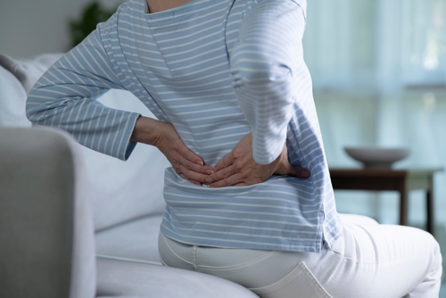 Person suffering from lower back pain on sofa